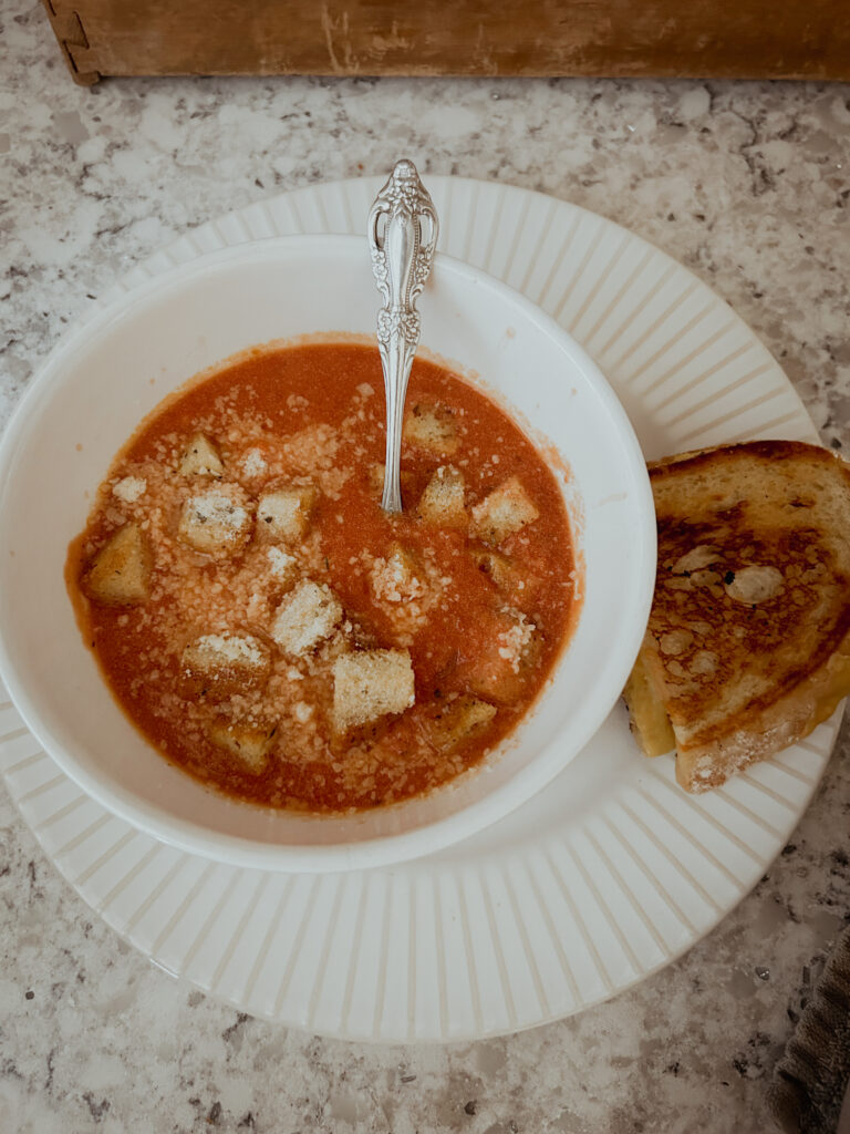 Creamy homemade tomato soup using canned crushed tomatoes. Topped with croutons and parmesan served with grilled cheese.