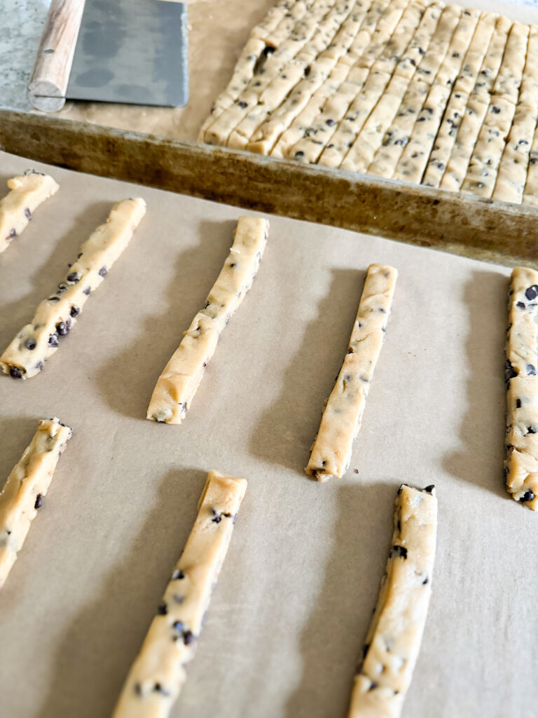 raw chocolate chip cookie dough cut into fry shape ready to bake.